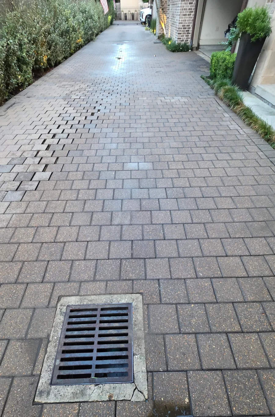 After: the same paver driveway seen from the drain, with the hydraulic fluid trail removed